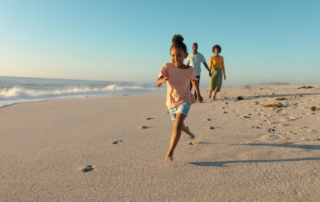 A family running on the beach during an Oregon summer vacation to Newport.