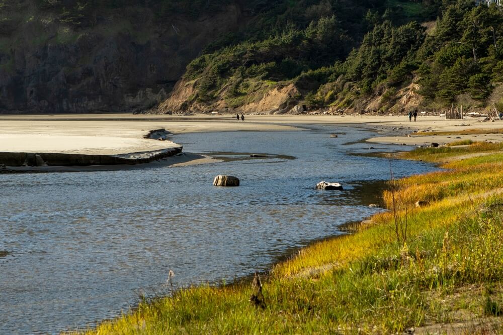 People in the distance walking on a beach in Newport, Oregon.